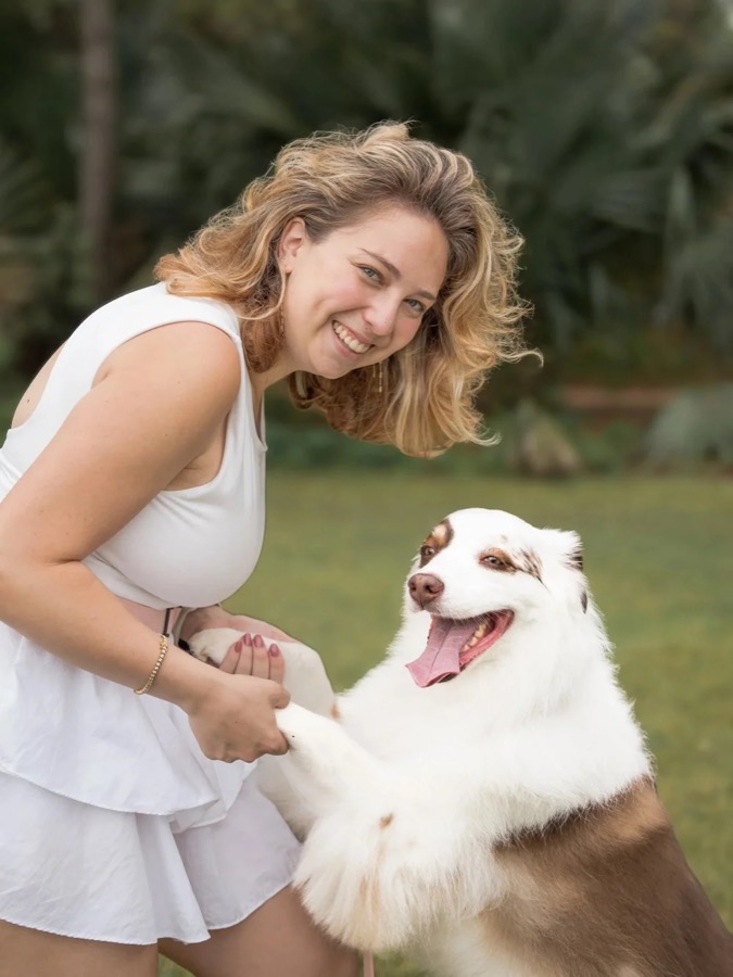 Alex laughing and shaking paws with an Australian shepherd